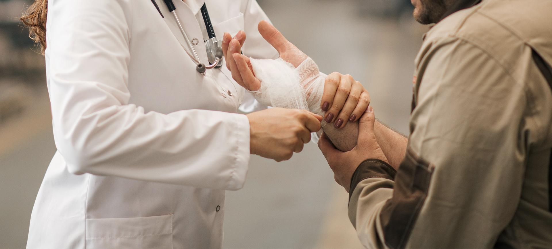 doctor wrapping injured patient's hand in a warehouse