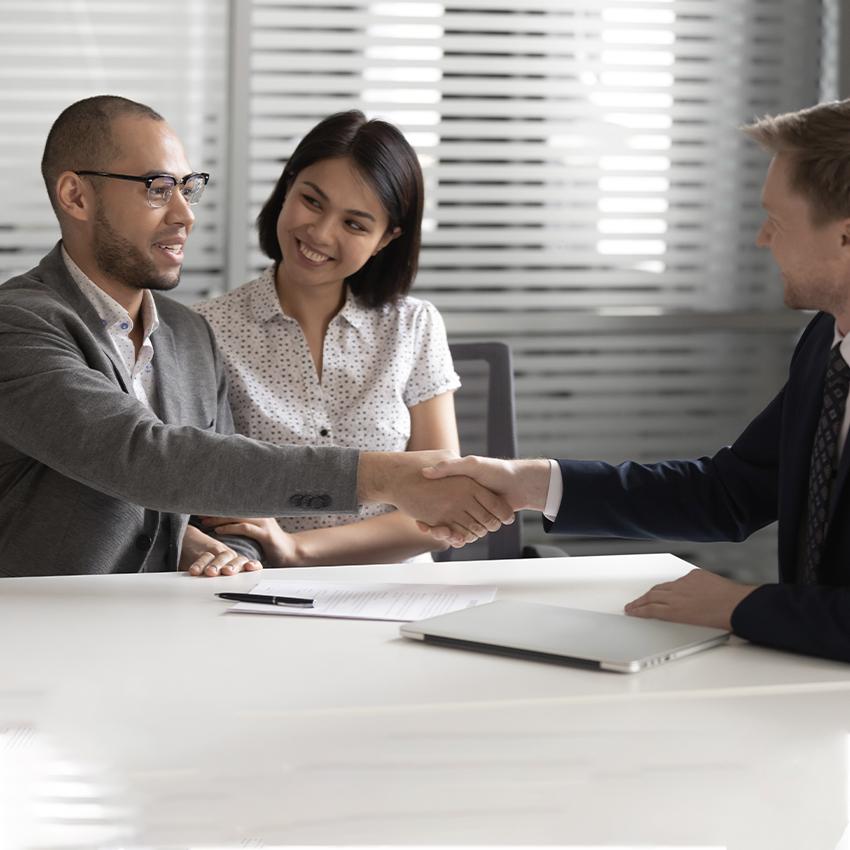 smiling couple shaking hands with lawyer